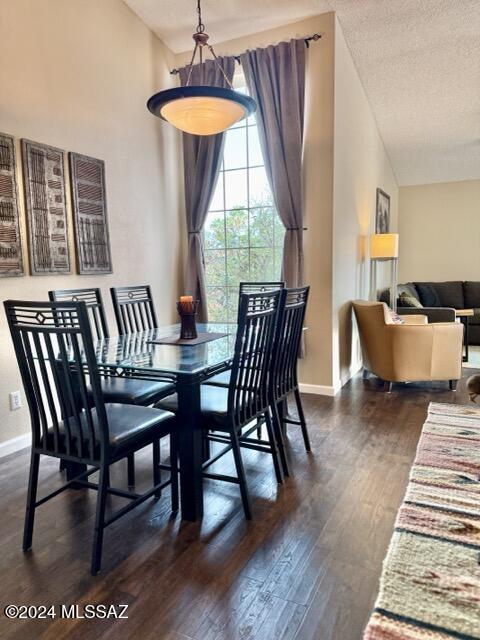 dining space featuring a textured ceiling, dark wood-type flooring, and vaulted ceiling