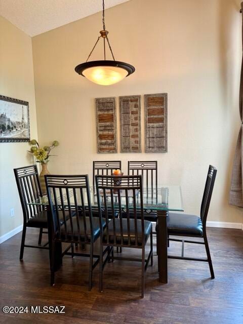 dining area with dark wood-type flooring and vaulted ceiling