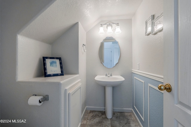 bathroom featuring a textured ceiling and vaulted ceiling