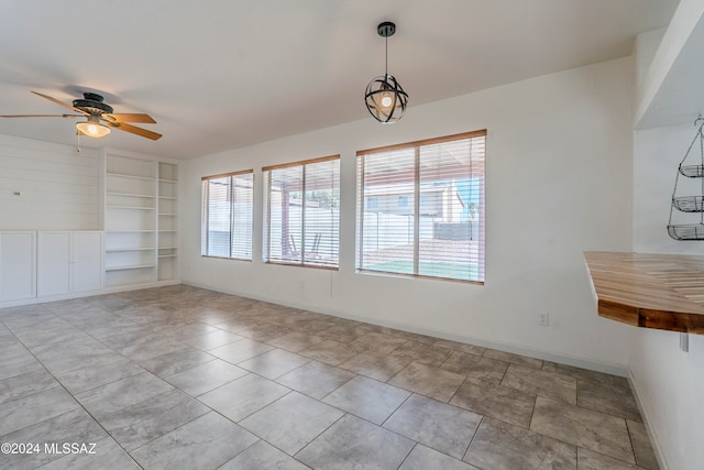 unfurnished dining area with built in shelves and ceiling fan