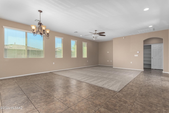 tiled empty room featuring ceiling fan with notable chandelier and a wealth of natural light