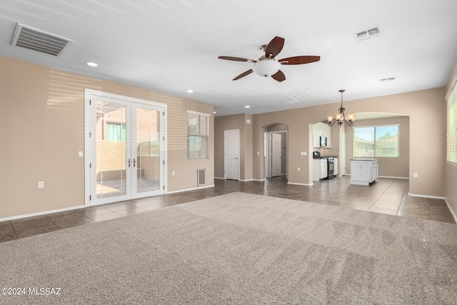 unfurnished living room featuring french doors, light colored carpet, and ceiling fan with notable chandelier