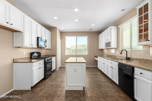 kitchen with black appliances, sink, a kitchen island, light stone counters, and white cabinetry