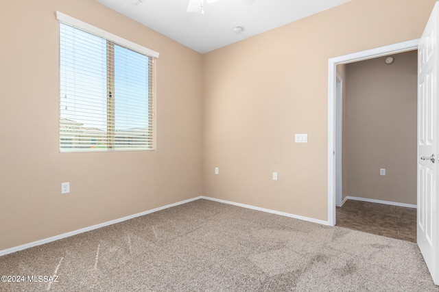 empty room featuring ceiling fan and carpet