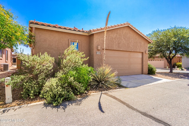 view of front of home with a garage and central air condition unit