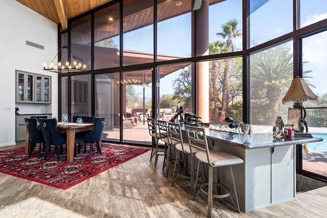 dining area with hardwood / wood-style floors, wooden ceiling, a high ceiling, and a chandelier