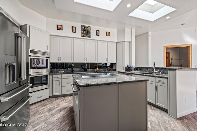 kitchen with a skylight, gray cabinetry, a kitchen island, and stainless steel appliances