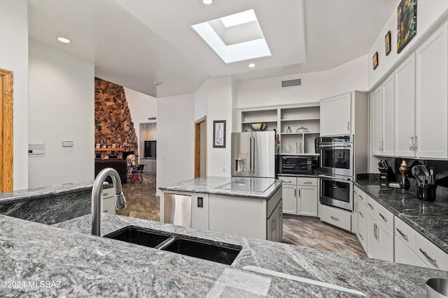 kitchen with a kitchen island, dark stone countertops, white cabinetry, and stainless steel appliances