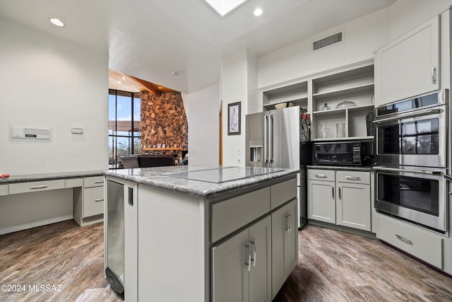 kitchen featuring a center island, hardwood / wood-style flooring, light stone counters, and black appliances