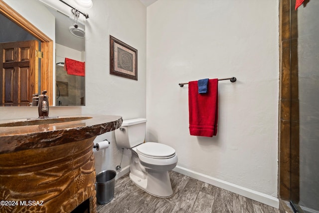 bathroom featuring wood-type flooring, vanity, toilet, and an enclosed shower