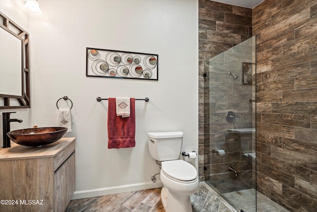 bathroom with a tile shower, toilet, vanity, and hardwood / wood-style flooring