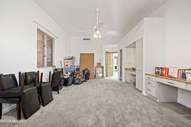 miscellaneous room featuring ceiling fan, light colored carpet, and built in desk