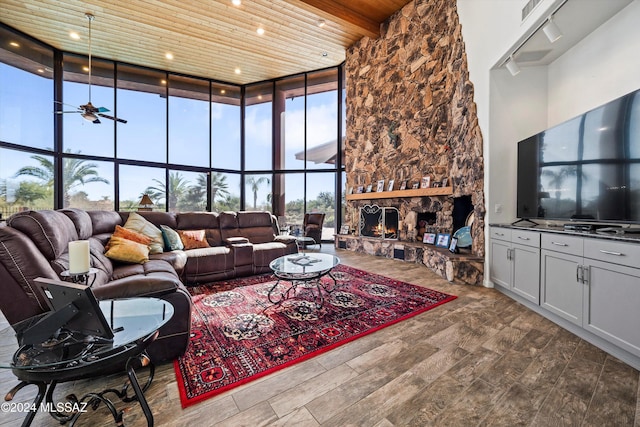 living room with ceiling fan, hardwood / wood-style floors, wooden ceiling, a fireplace, and a high ceiling