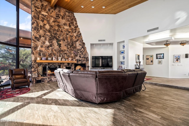 living room featuring wood-type flooring, high vaulted ceiling, a stone fireplace, and wooden ceiling