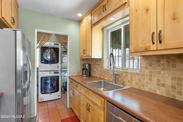 kitchen featuring sink, stainless steel appliances, backsplash, stacked washer / drying machine, and light tile patterned floors