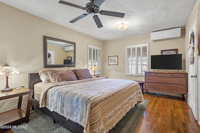 bedroom with a wall mounted AC, ceiling fan, and dark hardwood / wood-style flooring