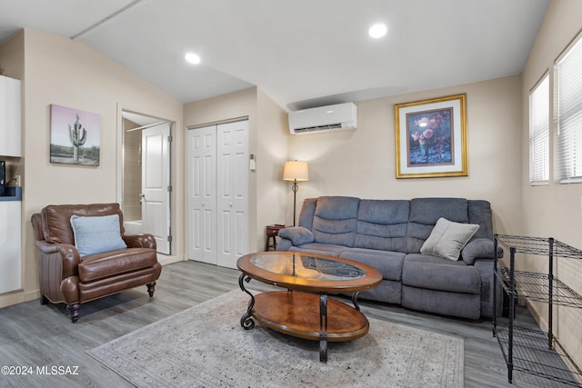 living room featuring hardwood / wood-style floors, lofted ceiling, and a wall unit AC