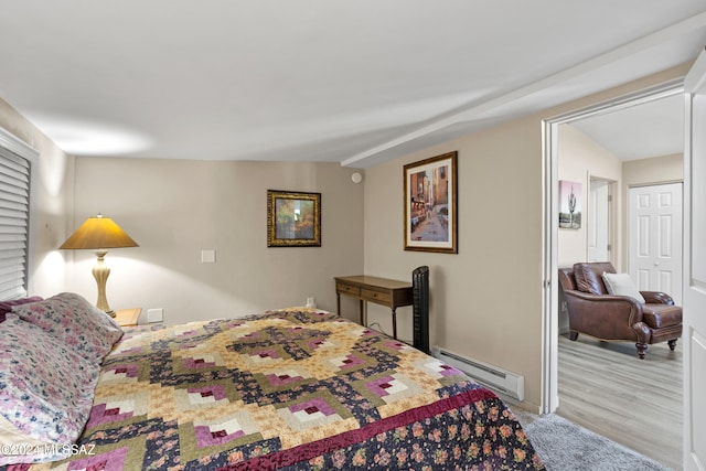 bedroom featuring lofted ceiling, a baseboard radiator, and light hardwood / wood-style floors