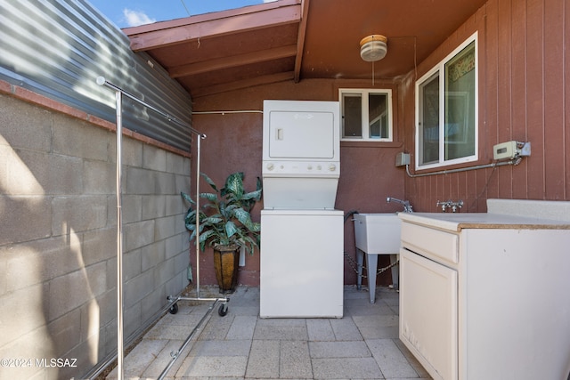 laundry area featuring wooden walls and stacked washer and clothes dryer