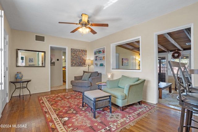 living room featuring beamed ceiling, wood-type flooring, ceiling fan, and wood ceiling