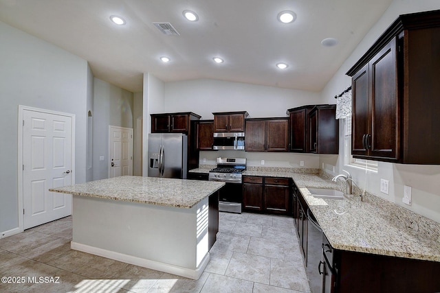 kitchen with light stone counters, stainless steel appliances, visible vents, dark brown cabinetry, and a sink