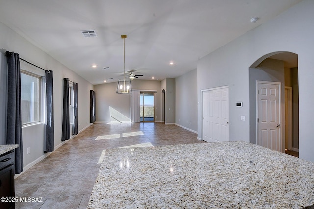 interior space featuring ceiling fan, a kitchen island, light stone countertops, and decorative light fixtures