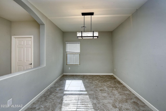 spare room with baseboards, visible vents, and arched walkways