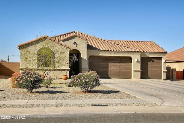 mediterranean / spanish-style home featuring a tile roof, stucco siding, concrete driveway, an attached garage, and fence