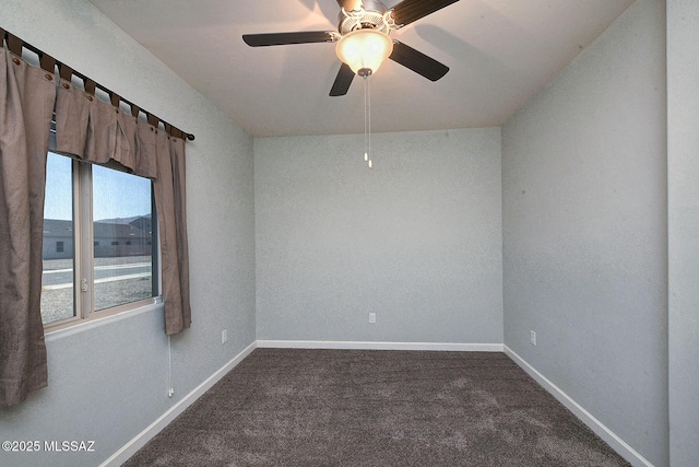 empty room with dark colored carpet, ceiling fan, and baseboards