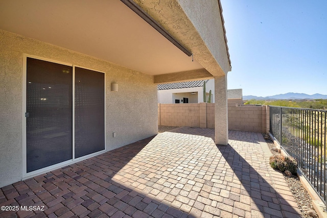 view of patio with a mountain view and fence