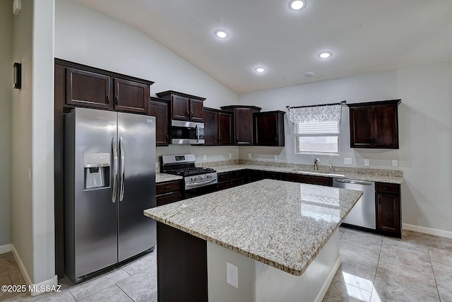 kitchen with a center island, lofted ceiling, sink, light stone countertops, and stainless steel appliances