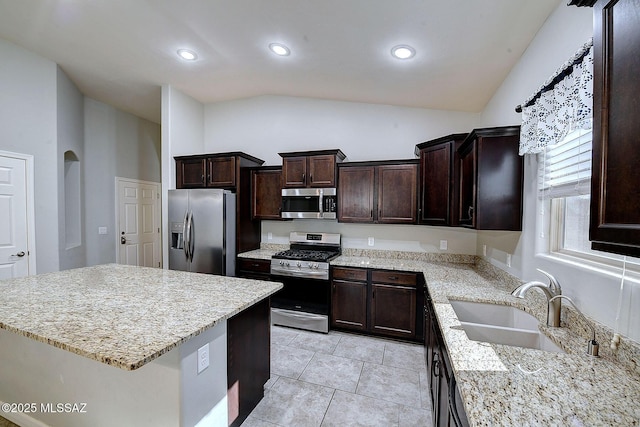 kitchen featuring light stone countertops, appliances with stainless steel finishes, sink, a kitchen island, and light tile patterned flooring