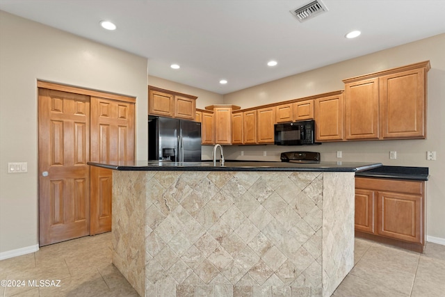 kitchen with light tile patterned floors, sink, an island with sink, and black appliances