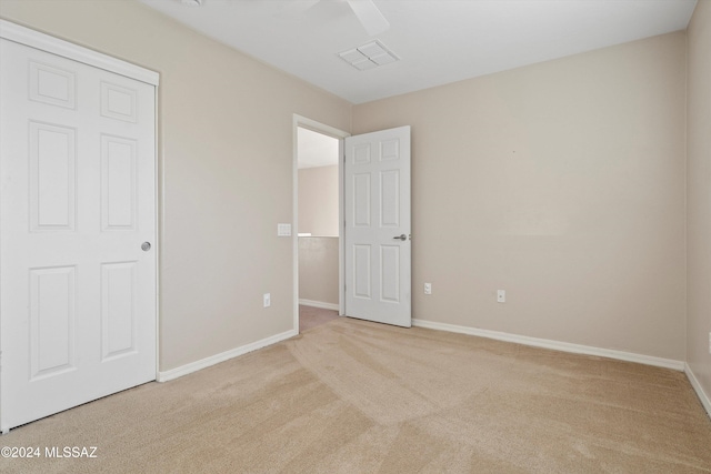 unfurnished bedroom featuring light carpet, a closet, and ceiling fan