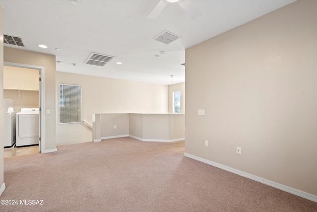 unfurnished room featuring washer and dryer, light colored carpet, and ceiling fan