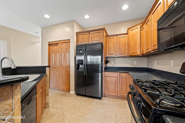 kitchen with black appliances, light tile patterned flooring, sink, and dark stone counters