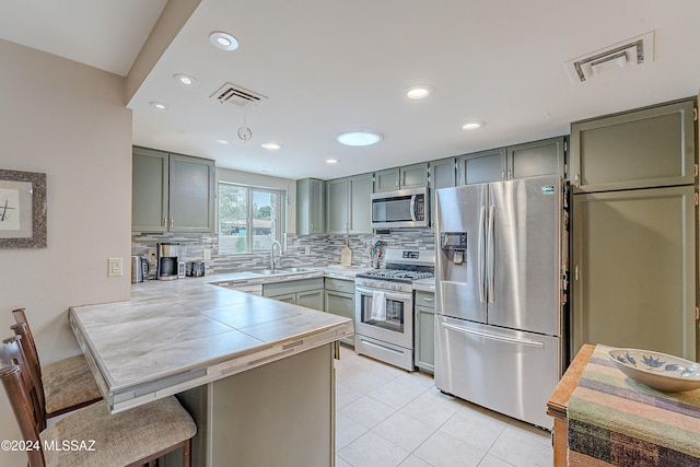 kitchen with sink, tasteful backsplash, kitchen peninsula, a kitchen bar, and appliances with stainless steel finishes