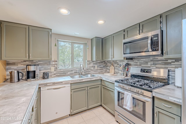 kitchen featuring appliances with stainless steel finishes, tasteful backsplash, light tile patterned floors, and sink