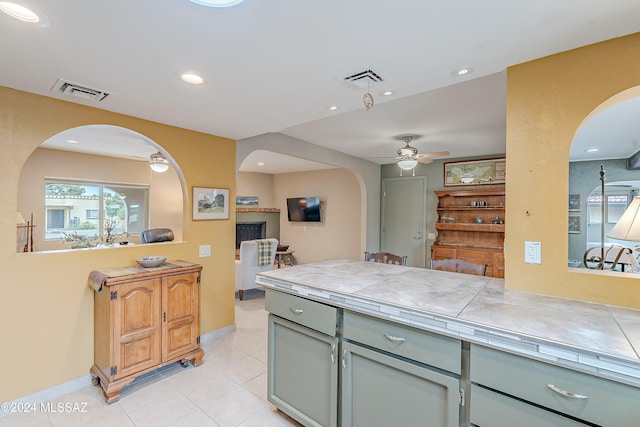 kitchen with light tile patterned floors, tile counters, and ceiling fan