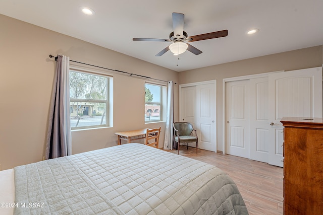 bedroom featuring multiple closets, ceiling fan, and light wood-type flooring