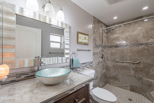 bathroom with tiled shower, decorative backsplash, vanity, and toilet