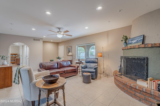 living room featuring ceiling fan, light tile patterned floors, and a brick fireplace