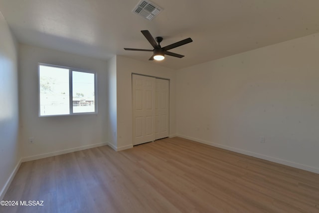 unfurnished bedroom featuring ceiling fan, light hardwood / wood-style floors, and a closet