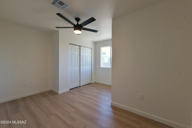 unfurnished bedroom with ceiling fan, light hardwood / wood-style floors, and a closet