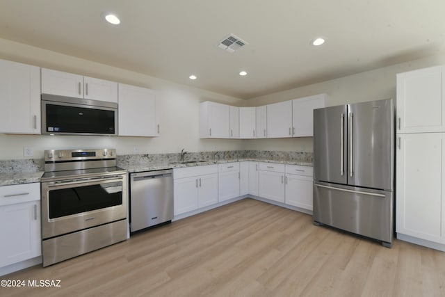 kitchen with appliances with stainless steel finishes, light hardwood / wood-style floors, and white cabinetry