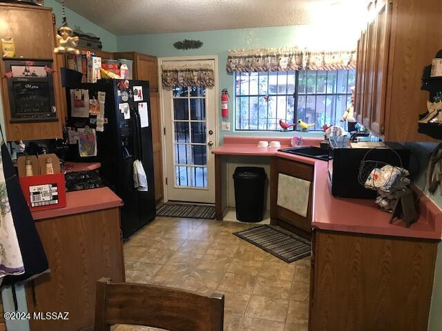 kitchen with a textured ceiling, sink, and vaulted ceiling