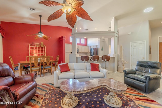 tiled living room with ceiling fan and high vaulted ceiling