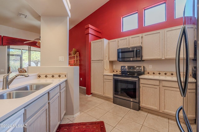 kitchen featuring light tile patterned floors, stainless steel appliances, light brown cabinetry, and sink