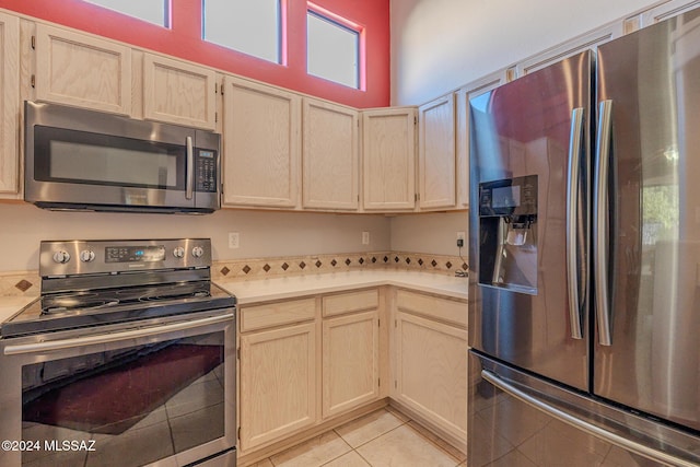 kitchen featuring light tile patterned floors, light brown cabinets, and stainless steel appliances