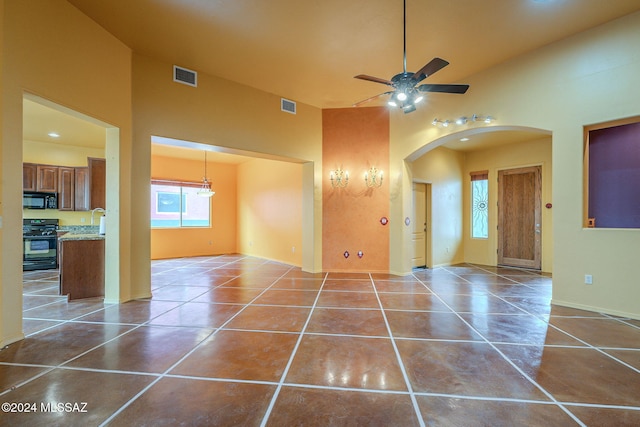 tiled empty room with ceiling fan, sink, and a high ceiling